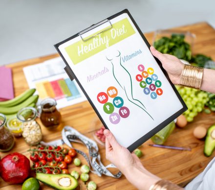 Holding a drawing with slim woman's figure with healthy food on the background. Healthy eating for slimming concept